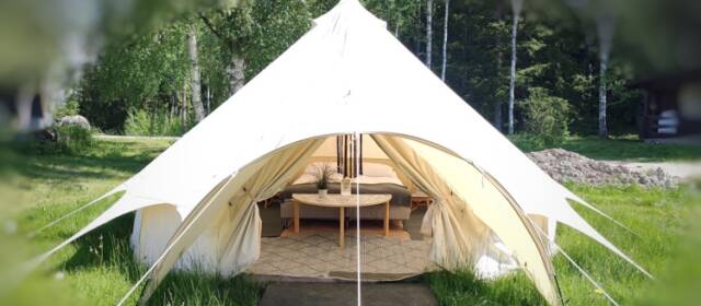 Korkea valkoinen glamping-luksusteltta jossa kalusteet