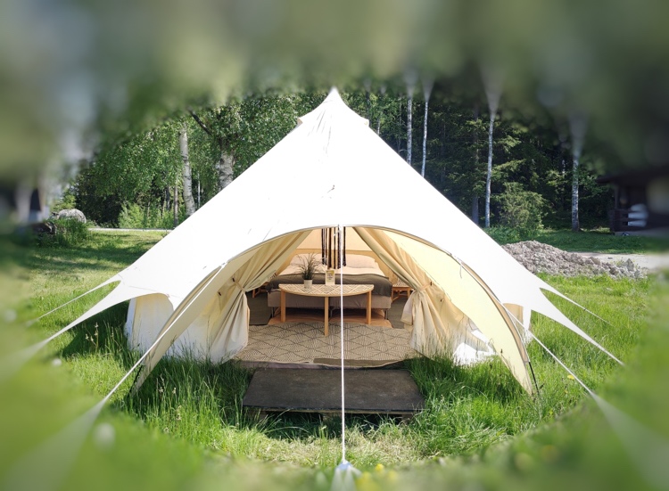 Korkea valkoinen glamping-luksusteltta jossa kalusteet